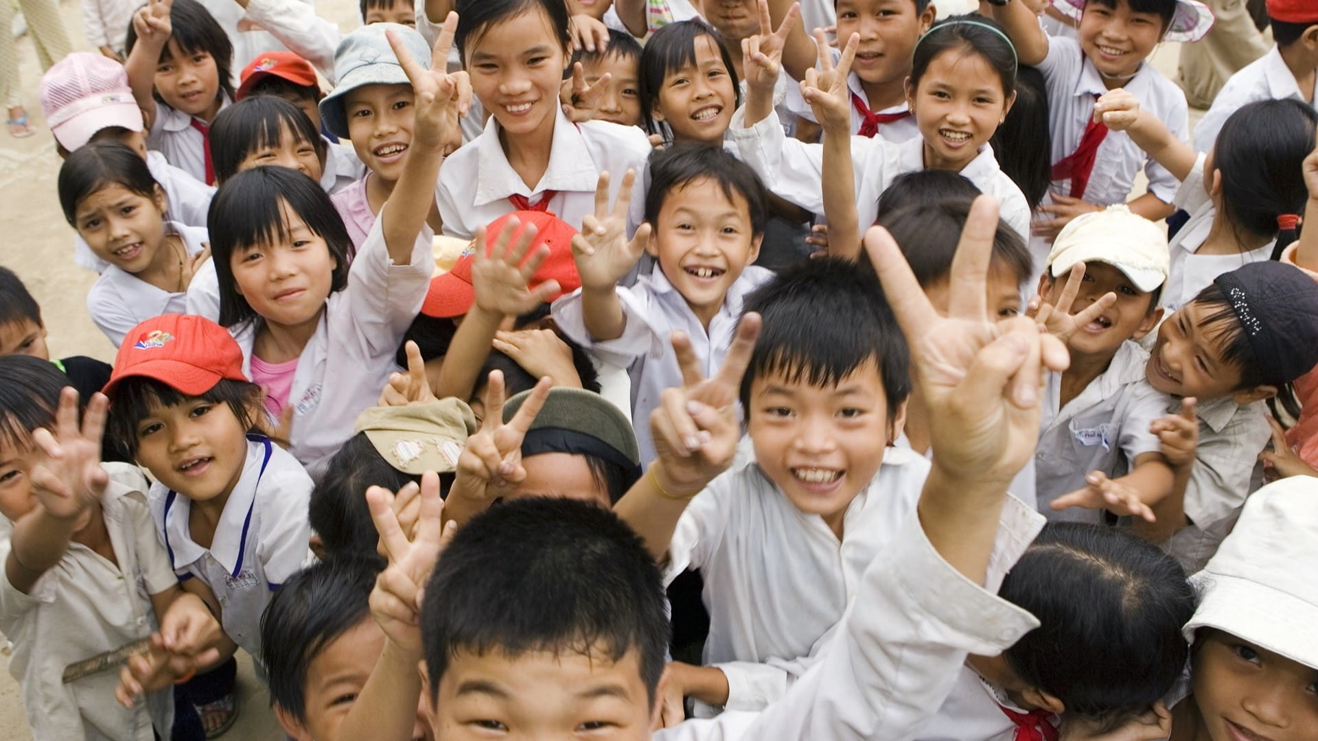 Vietnamese children gathered up smiling, making peace signs with their hands